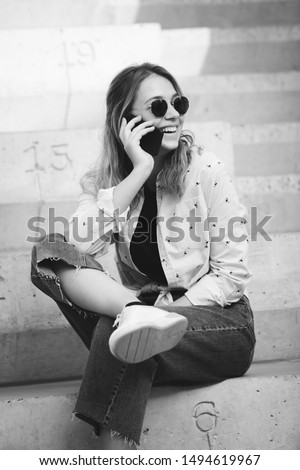 Portrait of a happy girl listening music on line with headphones from a smartphone in the street in a summer sunny day. Woman listening to music with the phone and having fun