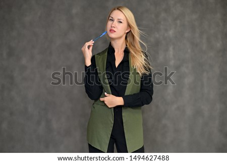Portrait of a pretty blonde girl in a dark suit on a gray background. Beauty, brightness, happiness, business look. Shows different emotions in different poses.
