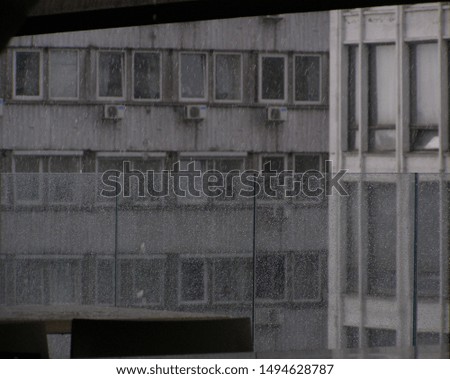 Picture of a soviet building taken on a rainy day on the top floor of a mall.