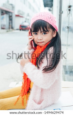 Happy Asian child little girl playing game on mobile phone. Concept Communication