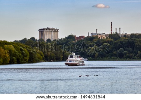 River motor ship and ducks floating on the river against the background of the cityscape