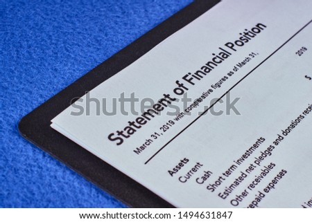 Sheet a statement of financial position in a black folder and pen on a blue velvet background Royalty-Free Stock Photo #1494631847