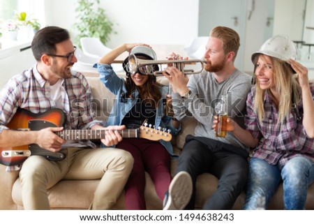 Group of young friends having fun together and playing in music band