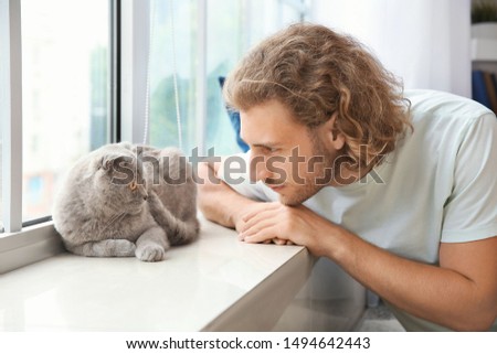 Man with cute funny cat near window