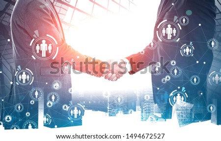 Close up of two unrecognizable businessmen shaking hands in modern city with double exposure of HUD social network interface. Toned image