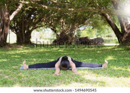 Young woman practicing yoga which uses the strength of the body to balance the body healthy lifestyle in the public park. Concept of relaxation for green nature.