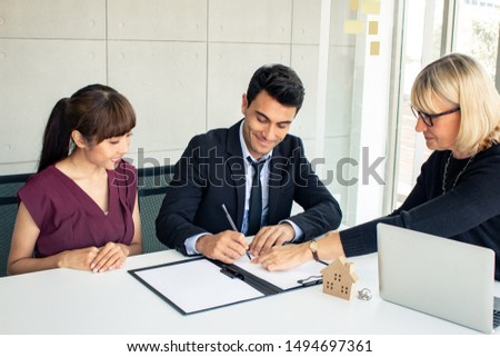 Customers consult with the owner on the contract of house sale.  Couples make purchasing a home with a company that can make a home. Husband and wife were signed to purchase a home.