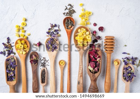 some wood spoon with herbal tea lavender, rose and chamomile on light wood table flat lay