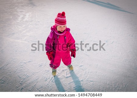 happy little girl learning to skate in winter