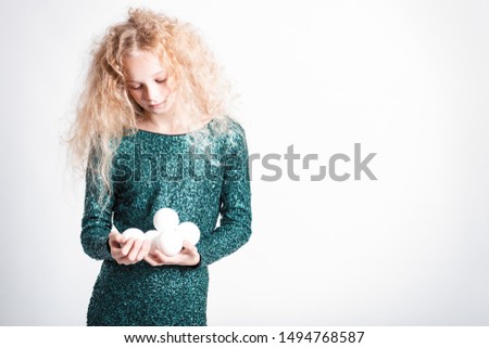 Merry Christmas and happy new year! happy girl with snow balls in hands looks very pleased. Close portrait isolated on white background