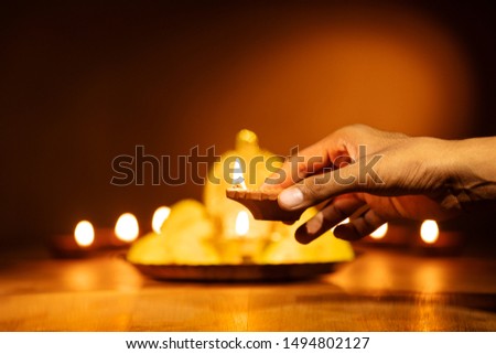 Hand with traditional Diwali lamps decoration for Diwali.