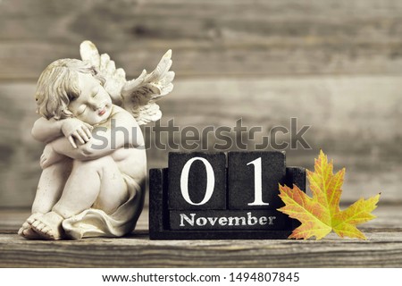 All Saints Day. Angel, wooden calendar and yellow autumn leaf Royalty-Free Stock Photo #1494807845