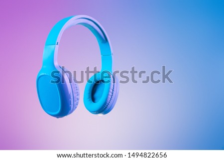 Stylish blue headphones on multi coloured / duo tone background lighting - lifestyle and fashion object concept image. Royalty-Free Stock Photo #1494822656