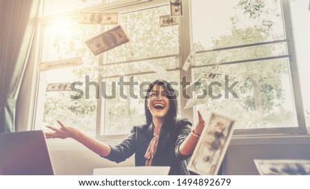 Happy businesswoman with around falling money in office