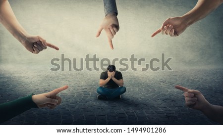 Stressed man, under pressure, sitting on floor cover face feel discomfort as a lot of hands pointing forefingers to him blaming as guilty. Human depression, social anxiety, victim of mental distress. Royalty-Free Stock Photo #1494901286