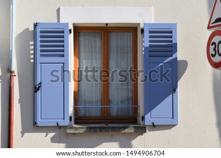 straight view of street detail: window with blue shutters and traffic signs
