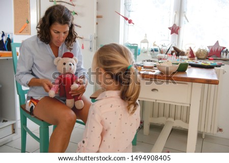Mother and daughter playing with teddy bear in the kitchen	
