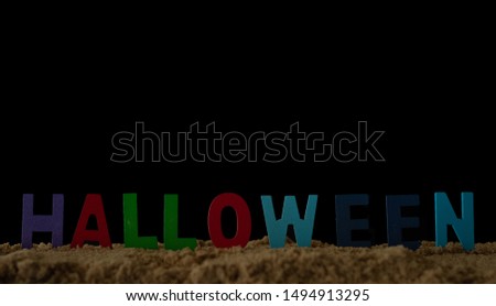 Alphabet Halloween in sand on black background,