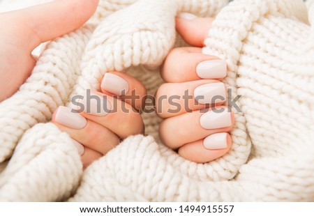 Stylish pastel beige Nails holding knitted wool material Royalty-Free Stock Photo #1494915557