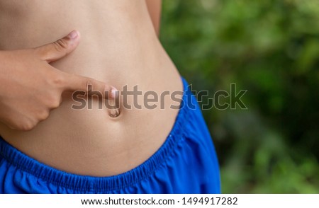  The boy's finger pointed to the navel hole,navel hole on the human stomach. Royalty-Free Stock Photo #1494917282