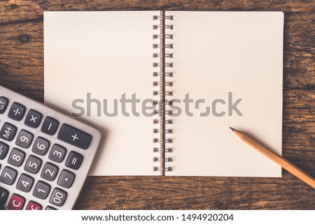 calculator and pencil over recycle book   on wooden table.