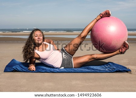 beautiful young woman doing pilates exercises with a ball