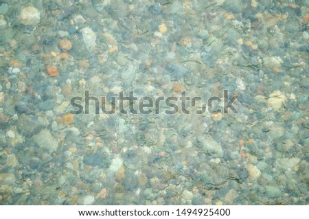 The surface of a clear river where you can see through the gravel