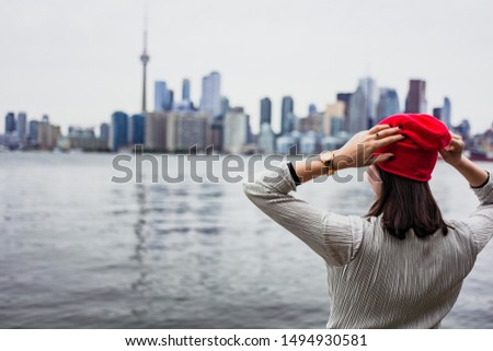 Woman traveler enjoying the view of Toronto city skyline with iconic landmarks and skyscrapers. Ferry ride to Centre Island. Rear view