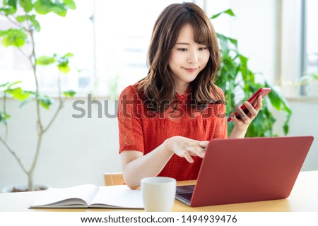 Attractive asian woman using a laptop PC and a smart phone. Royalty-Free Stock Photo #1494939476