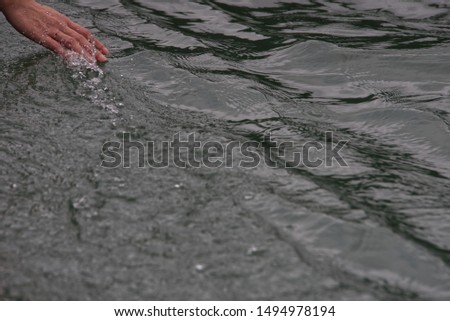 A people hand is touching flowing water surface