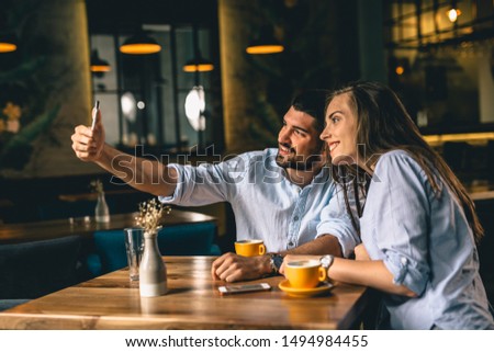 young couple taking picture with smartphone in restaurant