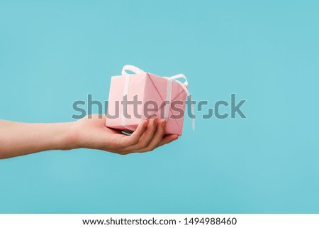 cropped view of woman holding gift box isolated on blue