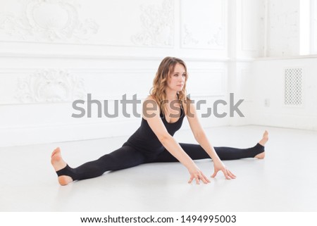 Cute teen touches the floor with her hands while doing splints