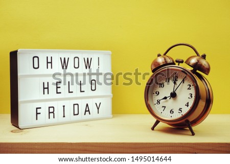 Hello Friday text in lightbox with alram clock on yellow background