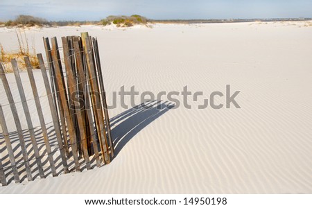 Coiled sand dune fence on beach with rippled sand