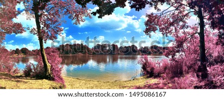 Beautiful pink and purple infrared panorama of a european countryside landscape with a blue sky