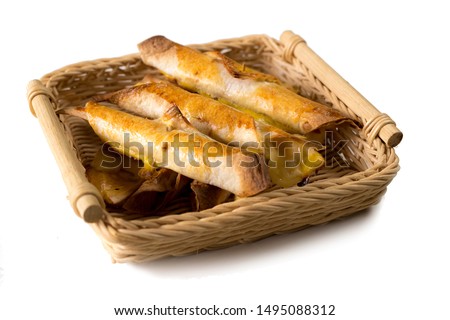 Batch of freshly baked taquitos in a wicker basket serving, on a white isolated background. Tasty mexican snack fresh out of the oven. Side view