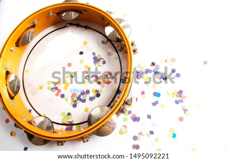 Tambourine, with chopped, colorful confetti, used in carnival.Solk party of samba.Instrument used in street blocks, parade of samba school.White background. From above.Space for your text. Royalty-Free Stock Photo #1495092221