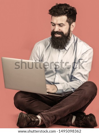 Happy young man sitting on the floor with and using laptop computer. Holding laptop computer.Young businessman using his laptop, pc.