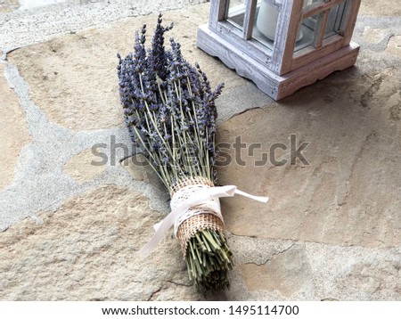 Bouquet of lavender on stone background next to white candle lantern