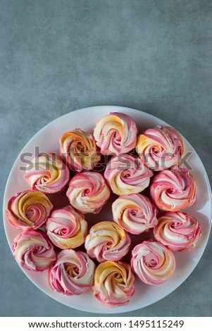 Beautiful bright multi-colored homemade marshmallow in the form of roses on a white plate. Top view. Soft focus.