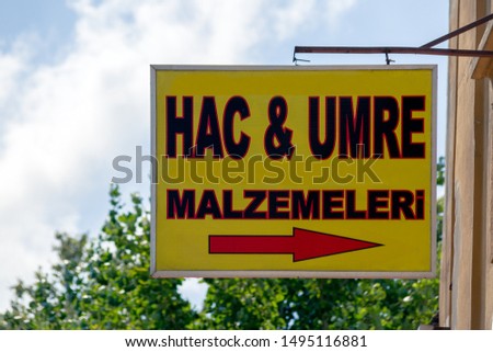 Street sign depicting Hajj and Umrah Accessories can be found at this direction. Jac ve Umre Malzemeleri in Turkish language means Hajj and Umrah Accessories.