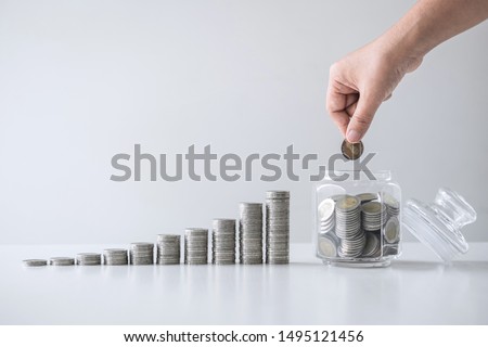 Images of growing stacking coins and Hand putting coin into glass bottle (money box) for planning step up and savings, Saving money for future plan and retirement fund concept. Royalty-Free Stock Photo #1495121456