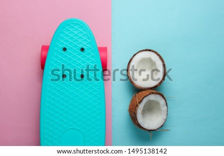 Creative summer concept. Skateboard, coconut halves on blue pink background. Pastel color trend. Copy space, top view