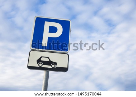 International traffic sign 'Parking' & sign showing the way of parking is below. Blue cloudy sky is on background