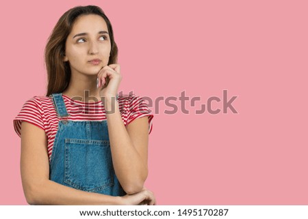 Portrait of a beautiful girl in a striped T-shirt, looks aside with pensive expression, is considering a plan for further action.