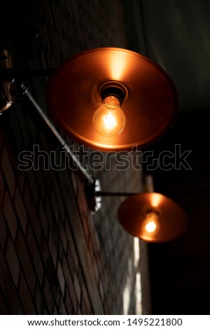 Old dim light in an old factory beside a brick wall.
