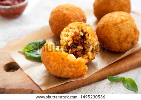 Homemade fried Arancini with basil and Marinara on a white wooden background, side view. Italian rice balls. Closeup. Royalty-Free Stock Photo #1495230536