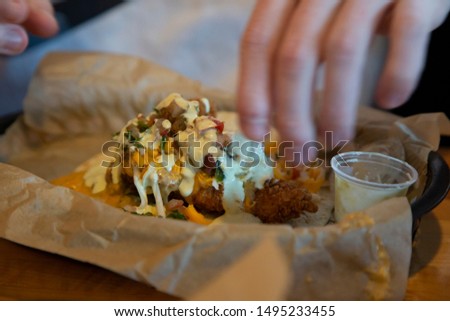 Fried chicken taco with pico de gallo, cheddar cheese, and white sauce in a soft shell