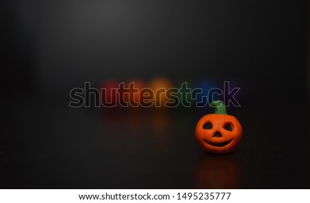 LGBT colored beads and Halloween pumpkin on black background soft focus